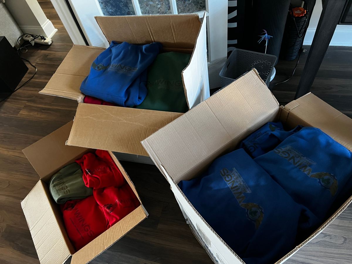 Boxes of embroidered WINGS Academy hoodies ready for delivery